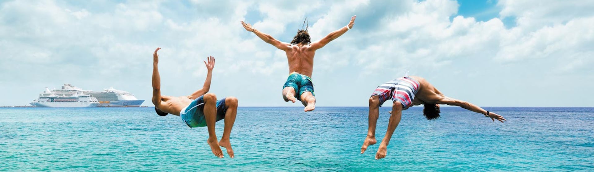 Tre killar hoppar i vattnet från en brygga i Cozumel, Mexiko.