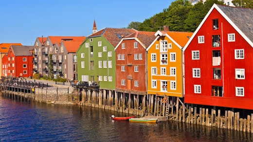 Solen ligger på de färgglada trähusen vid vattnet i Trondheim i Norge.