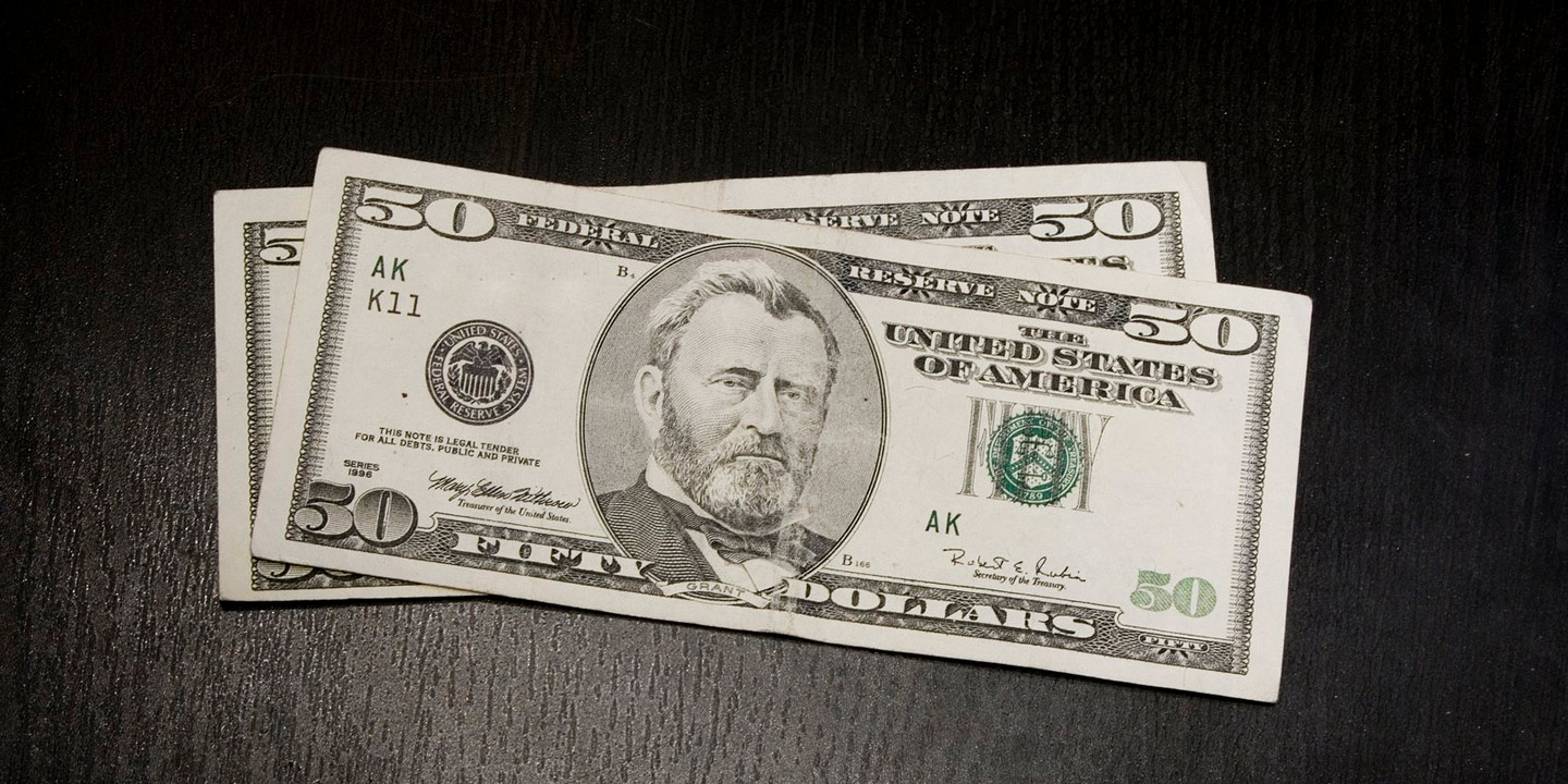 Amerikanska 50-dollarsedlar på ett bord.