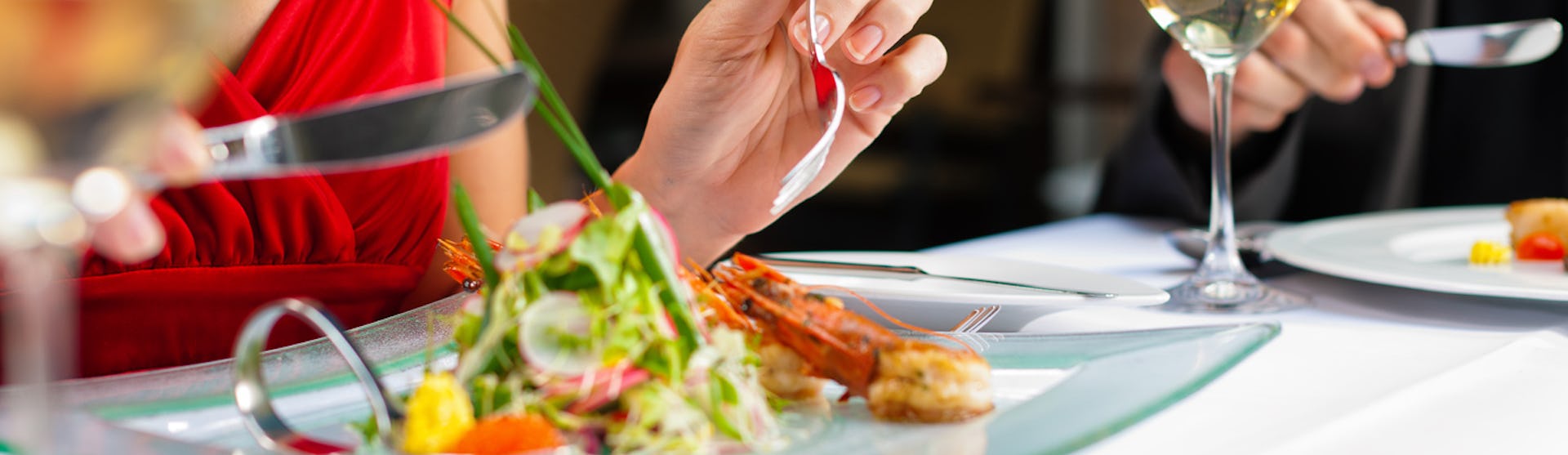 Kvinna i röd klänning med vackert upplagd mat på en tallrik framför sig.