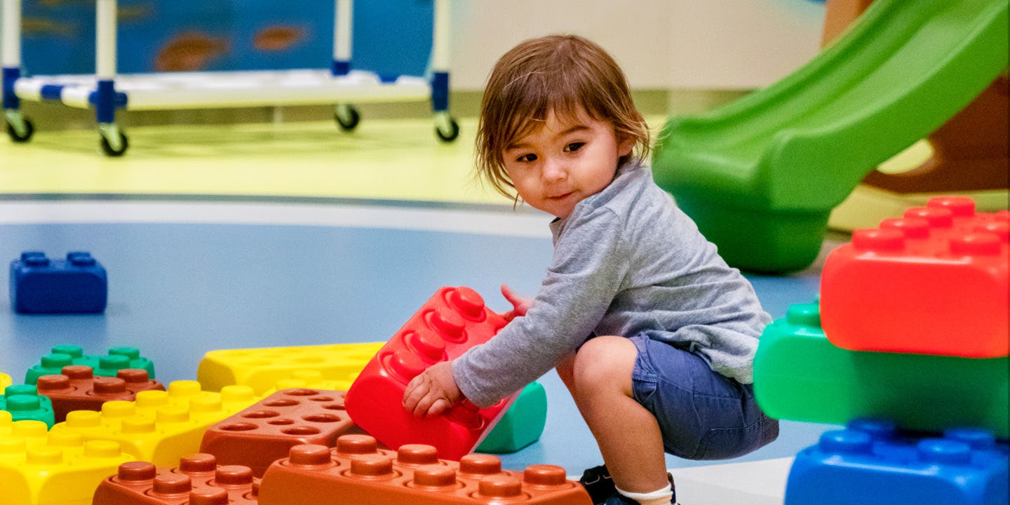 Liten resenär sitter och leker med over sized lego ombord på Royal Caribbeans fartyg.