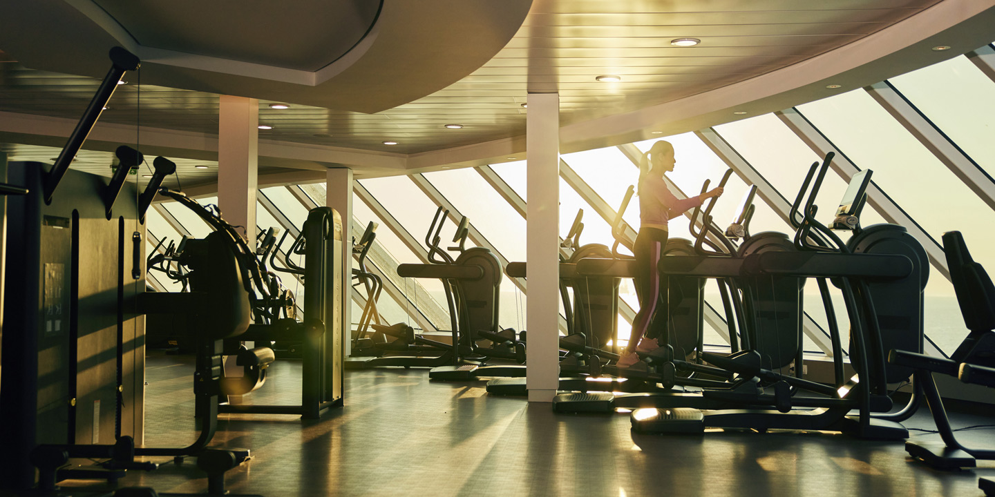 Kvinna på crosstrainer i Fitness Center ombord på fartyget Celebrity Beyond.