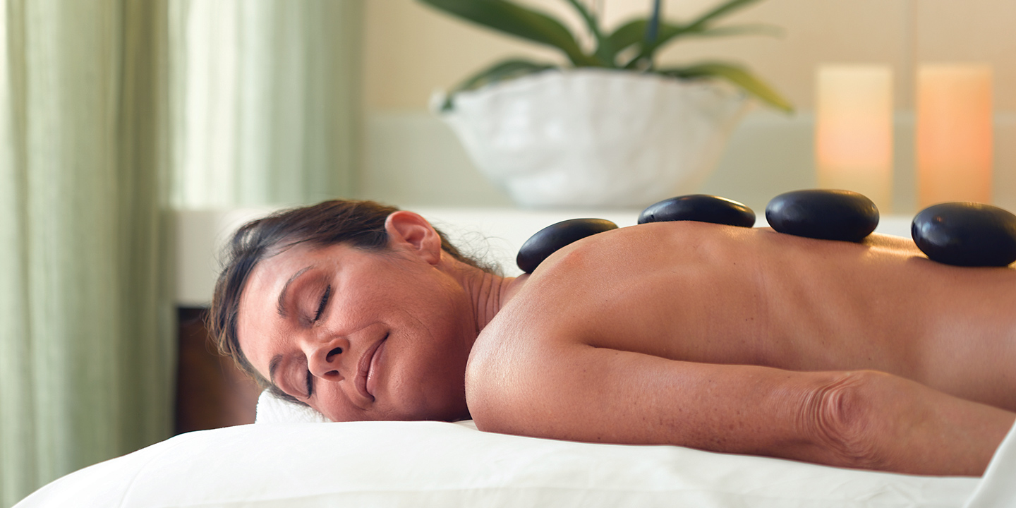Kvinna njuter av en hot stone-massage ombord på Oceania Cruises fartyg.