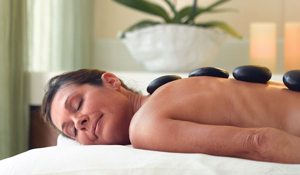 Kvinna njuter av en hot stone-massage ombord på Oceania Cruises fartyg.
