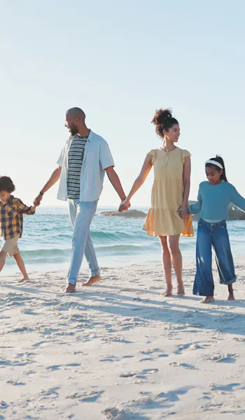 Stor familj håller hand på stranden.