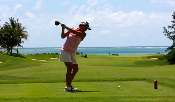 Kvinna ska precis slå ut golfbollen från tee.