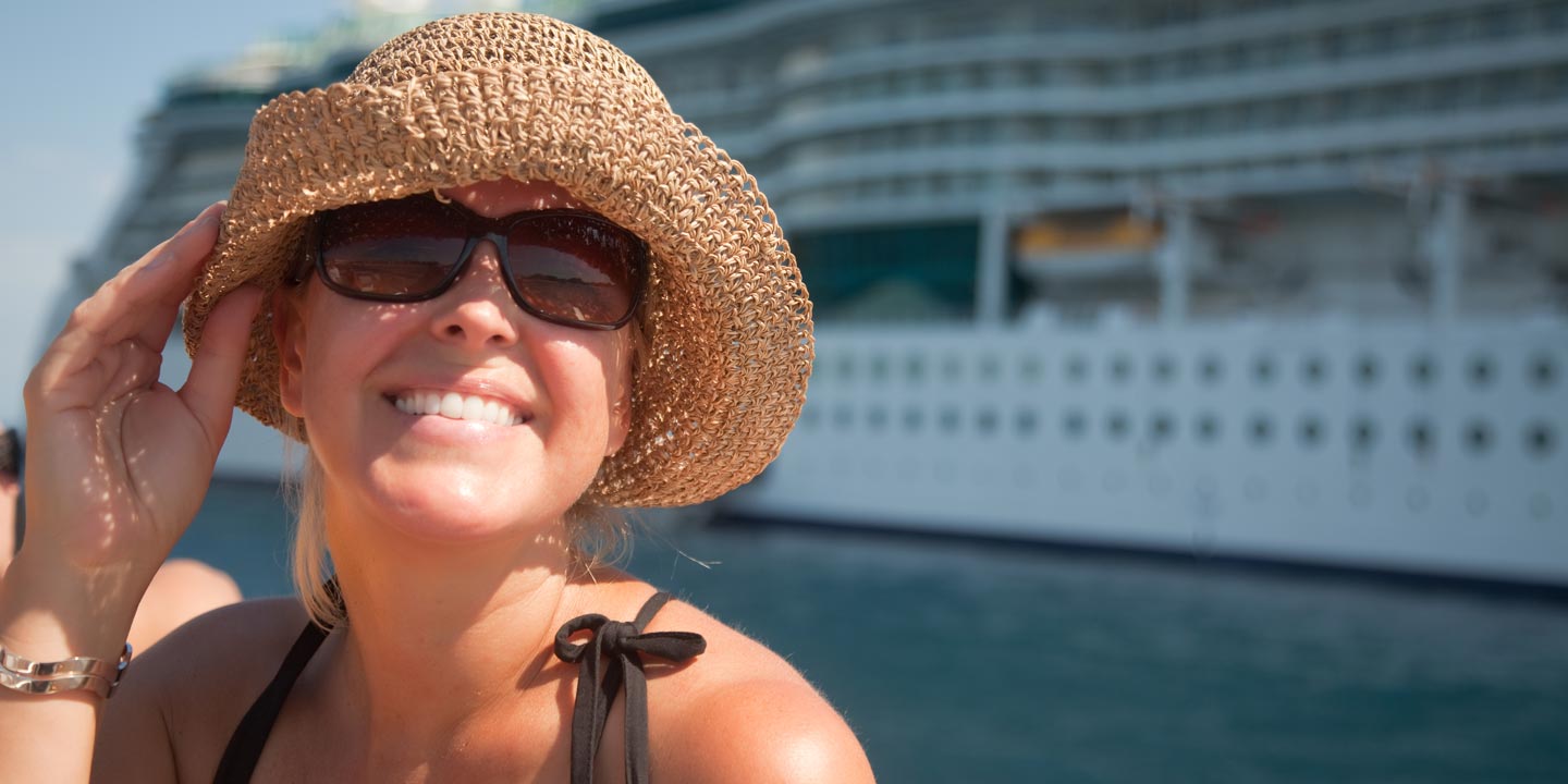 Glad kvinna framför ett kryssningsfartyg.