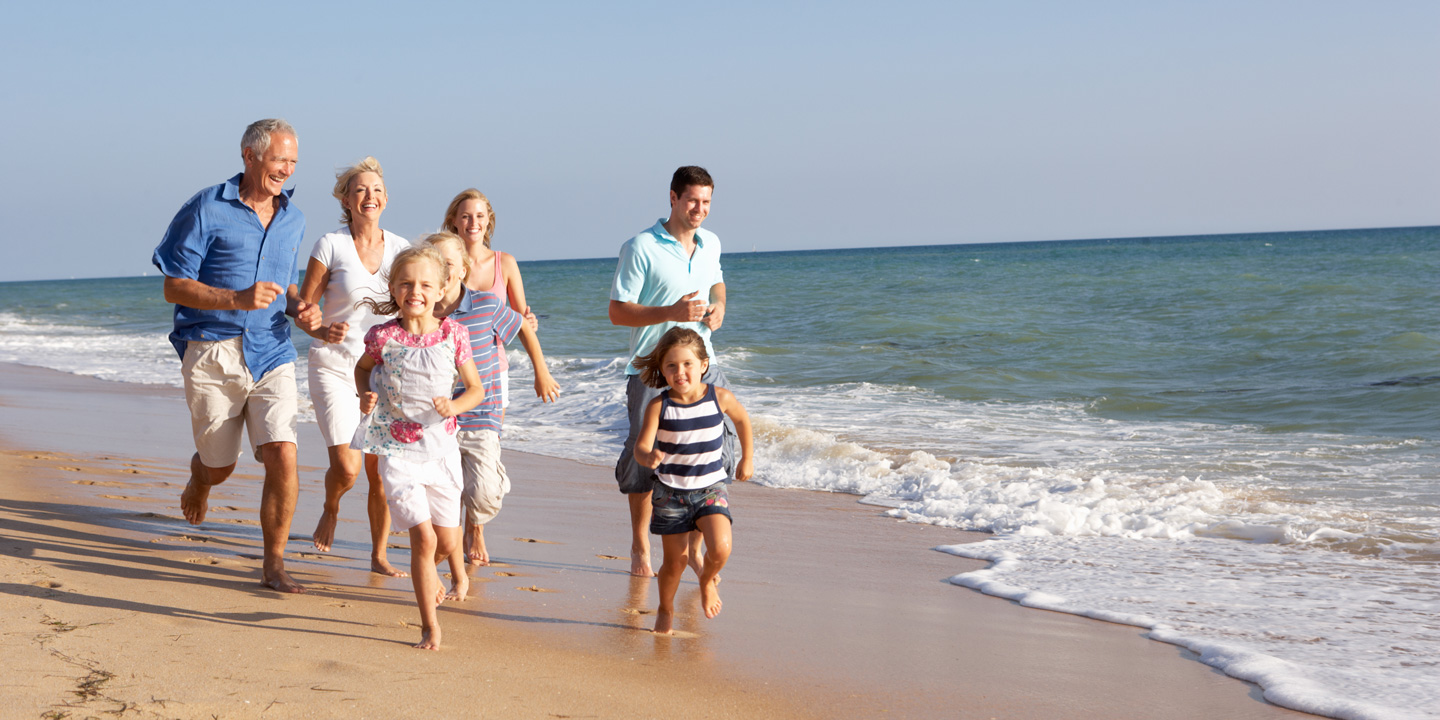 Familj i tre generationer, springandes på en strand.