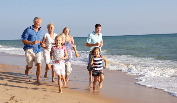 Familj i tre generationer, springandes på en strand.